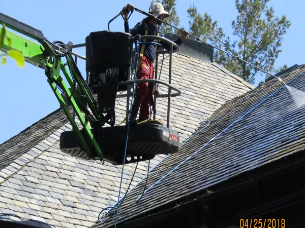 Technician cleaning a roof from a lift
