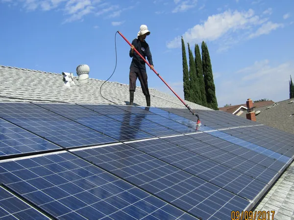 Technician cleaning rooftop solar panels